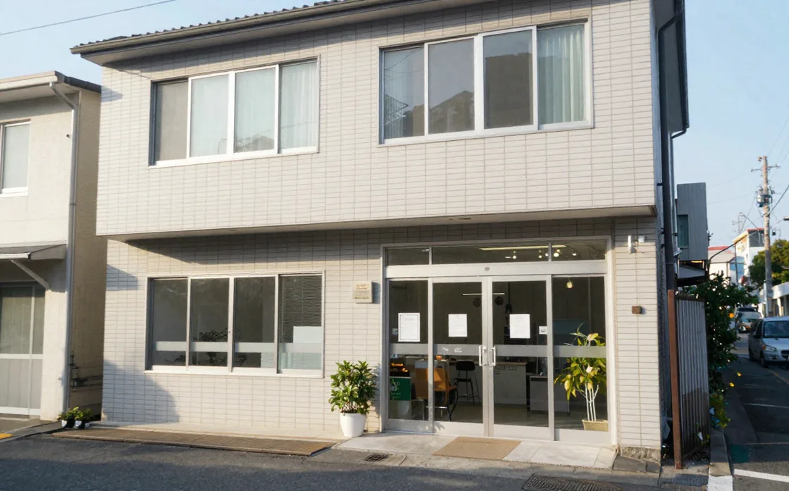 駅近くの小さなビルの外観。1階がガラス扉の事務所。自主制作サンプル用に生成したイメージ